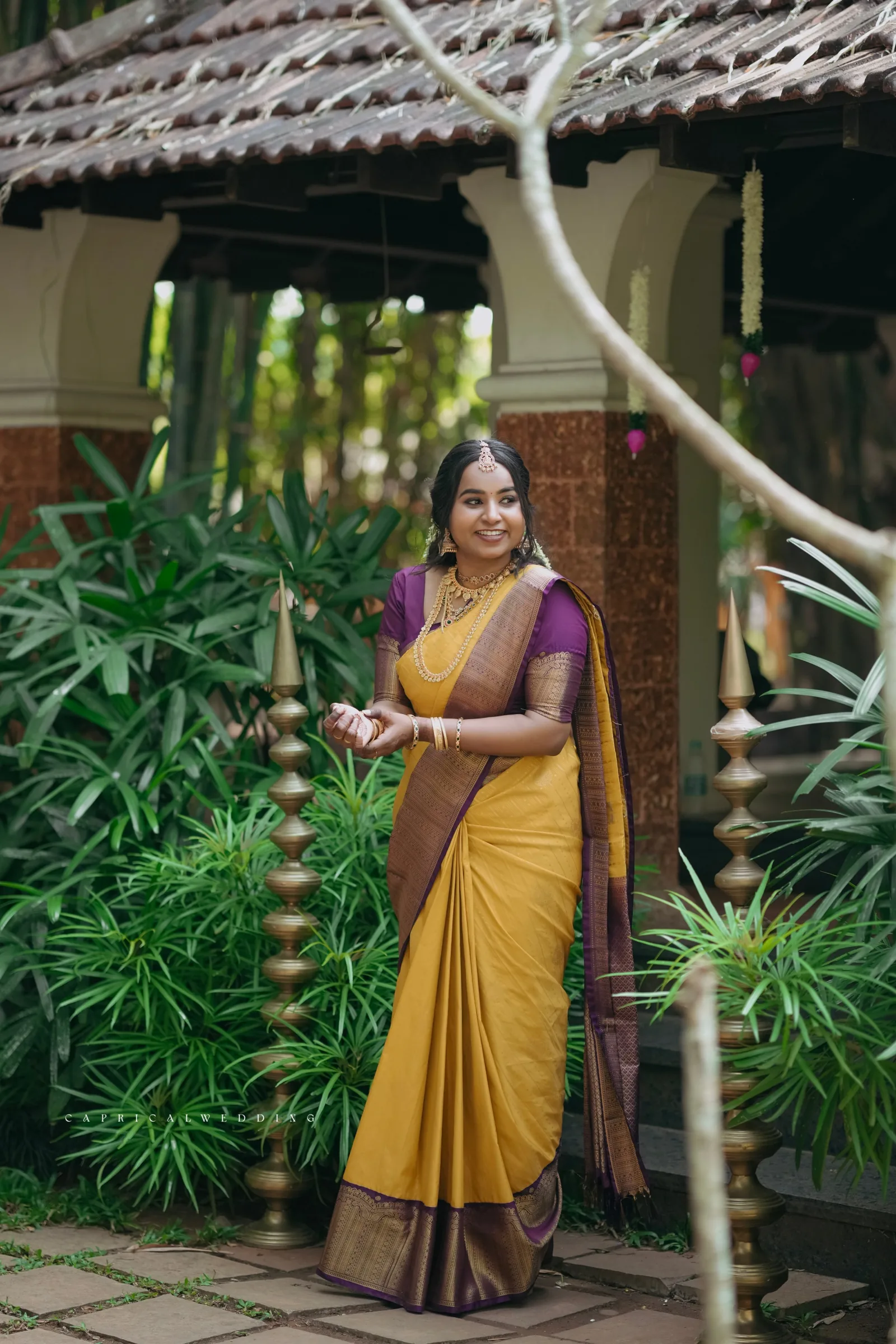 A bride in yellow and purple standing in a garden